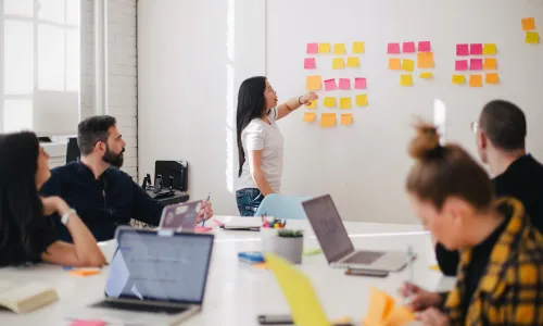 Woman placing sticky notes on wall — free license by Your X Ventures from Unsplash.com